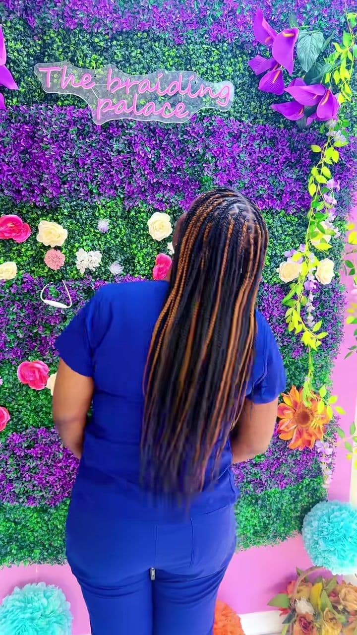Waist-length knotless braids in copper, seen from behind